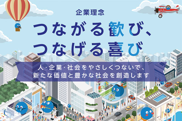 An illustrated image representing BIGLOBE's corporate philosophy in Japanese, featuring a vibrant cityscape with blue mascot characters, a hot air balloon, and an airplane. The main message in Japanese highlights the joy of connecting people, companies, and society to create new value and a prosperous society.
