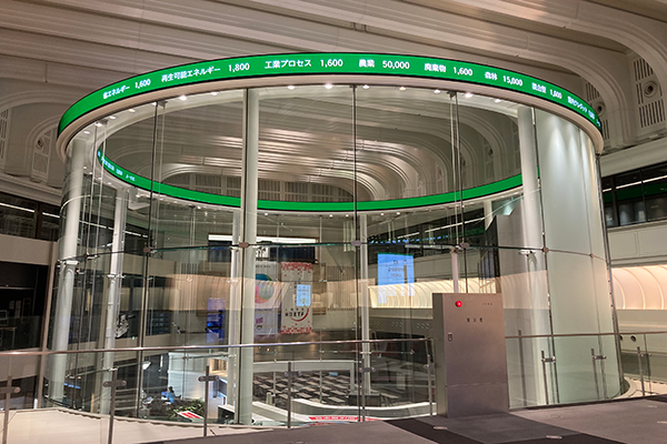 The interior of the Tokyo Stock Exchange featuring a modern circular glass rotunda with digital stock ticker displays.