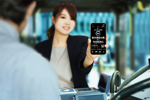 A woman demonstrates the LECIP mobile ticketing solution by showing a smartphone screen at a transportation access point in an AWS case study image.