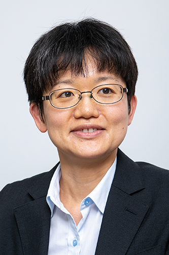 A professional portrait of an individual wearing glasses and a business suit, posed against a plain background.