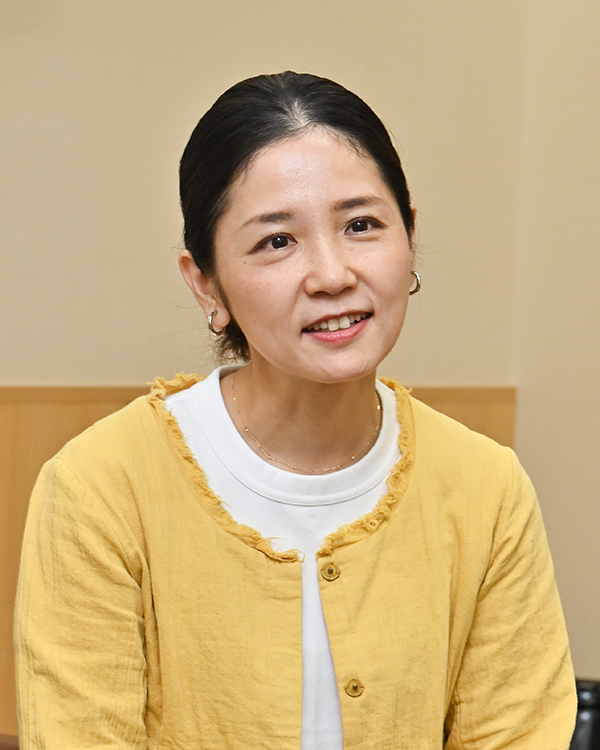 A portrait of a woman in a yellow jacket smiling during an interview for the Takihyo Takai case study.