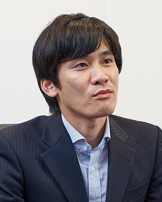 Portrait of a Japanese businessman in a suit during an interview, looking slightly to the side.
