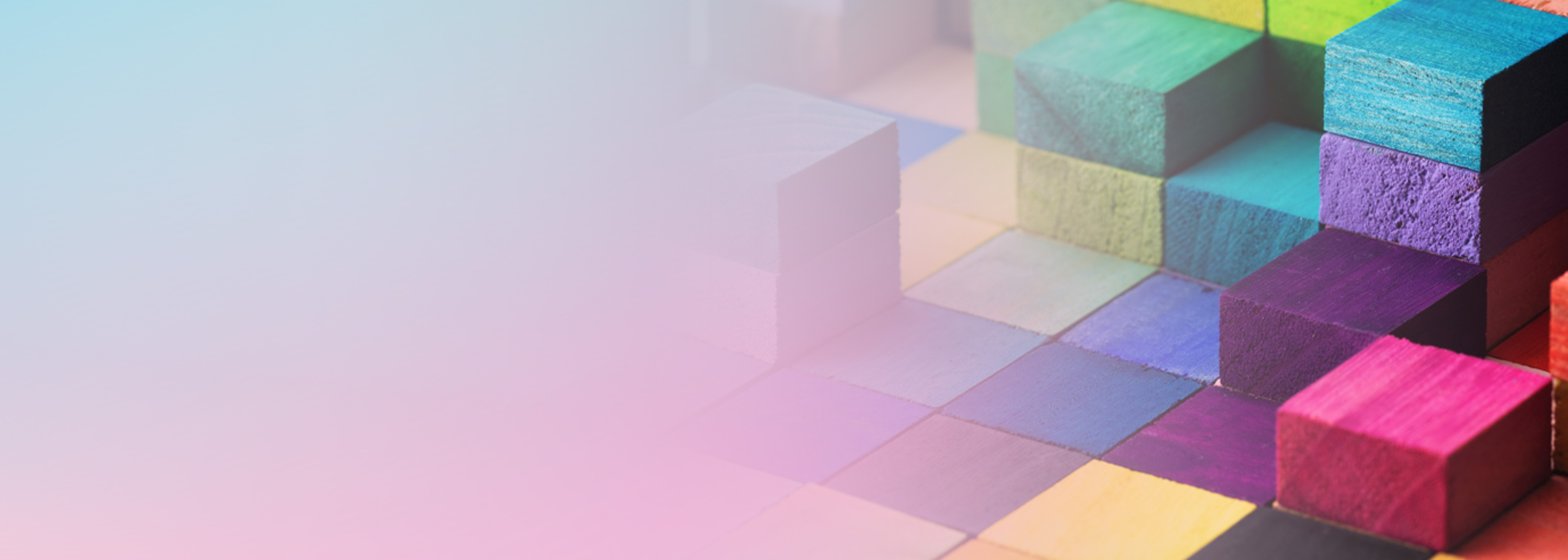 Abstract image featuring a variety of colorful wooden blocks stacked and arranged on the right, fading into a pastel gradient background on the left. Represents diversity, structure, and creativity, suitable for a service catalog or case study context.