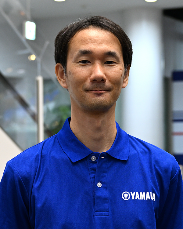 A person wearing a blue Yamaha-branded polo shirt in an indoor setting.