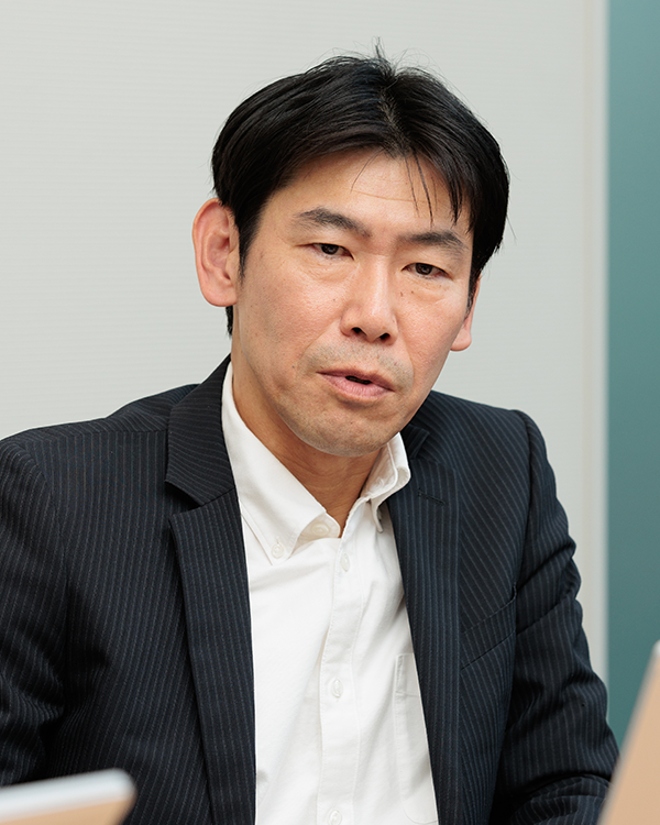 A person wearing a dark pinstripe suit and white collared shirt.