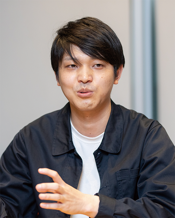 A person in a black jacket and white shirt engaged in a discussion, featured in the NTT Data solution case study for AWS Japan.