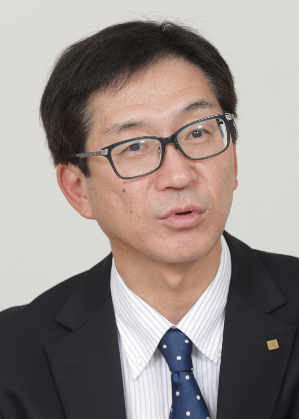 A person wearing a dark suit, striped shirt, and polka dot tie.
