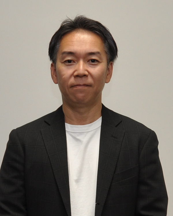 Portrait of a man in a black jacket and white shirt against a plain background