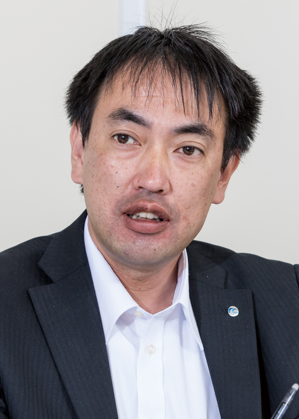 Executive portrait photograph of a person from M-Tech Nagano, shown in a suit and white shirt, taken for a case study or corporate profile.