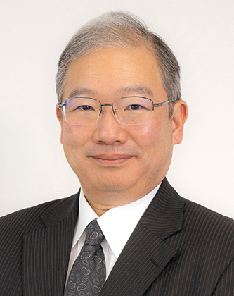 A professional headshot of a man wearing glasses and a business suit, smiling slightly, in front of a plain background.
