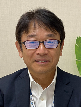 A portrait of a businessman with glasses, smiling indoors against a neutral background.