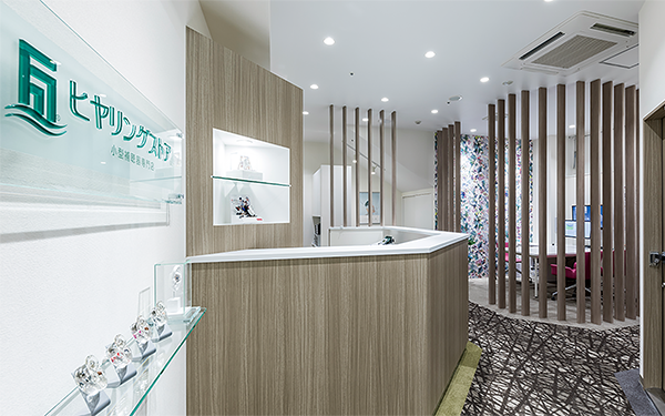 Modern reception area with wood paneling, glass shelves, and decorative vertical slats, featuring a floral accent wall in the background.
