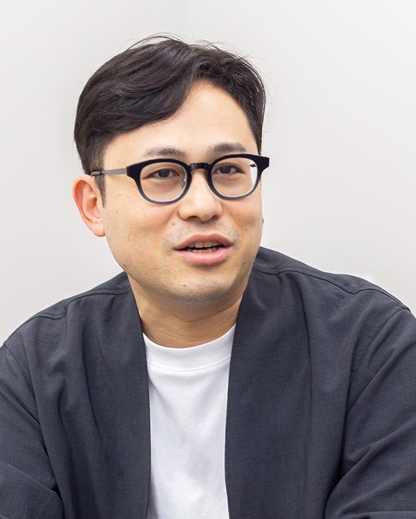 Portrait of an individual related to the Exnoa case study, wearing glasses and a dark jacket, photographed against a light background.