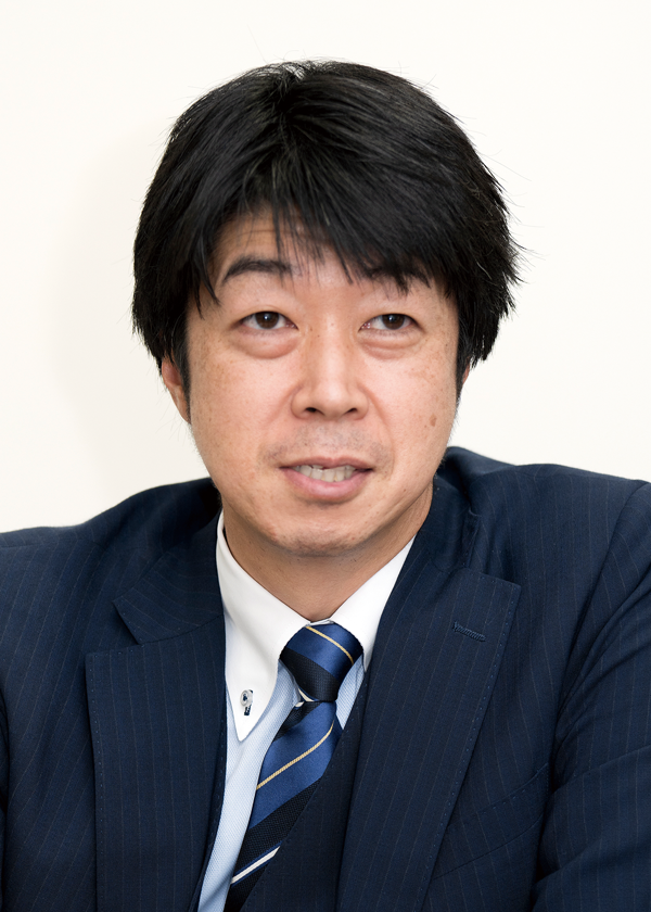 Business portrait of a man in a navy suit and striped tie, photographed against a plain background, associated with Yokohama Kawasaki.