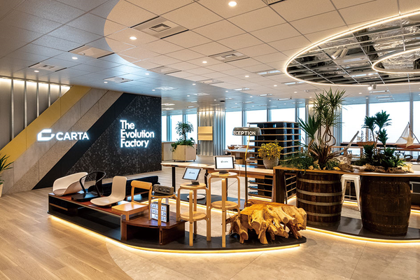 Modern office interior of Carta Holdings featuring a welcoming reception area with indoor plants, wooden tables, and contemporary seating, designed for a stylish and comfortable workplace environment.