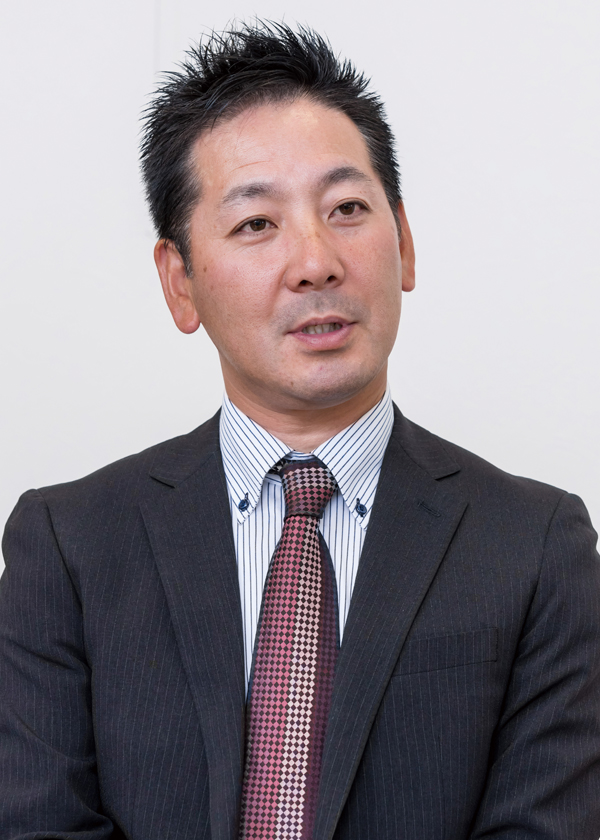 A business portrait of a professional man wearing a dark pinstripe suit and patterned tie, set against a plain background.