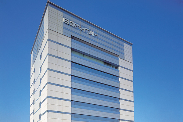 Exterior view of the Nippon Paint Holdings building against a clear blue sky.