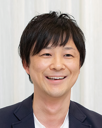 Portrait of a smiling man in business attire, photographed against a light background.