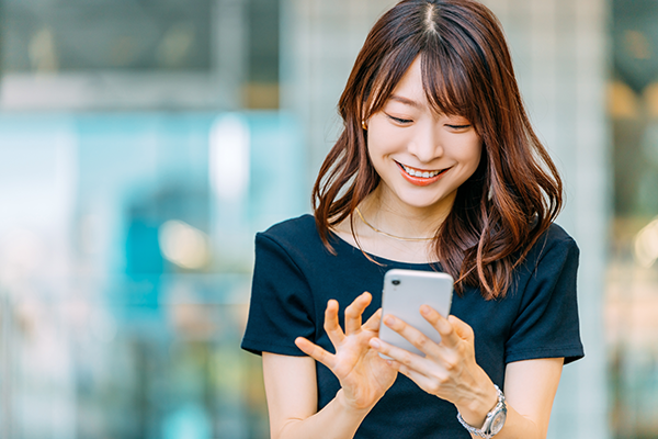 A person smiling while using a smartphone, representing user interaction and mobile technology for the SoftBank case study.
