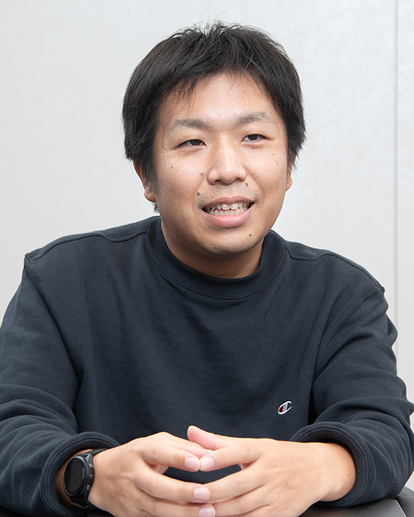 A person in a dark sweatshirt sitting at a table, facing forward, used as a portrait for the Mixi case study.