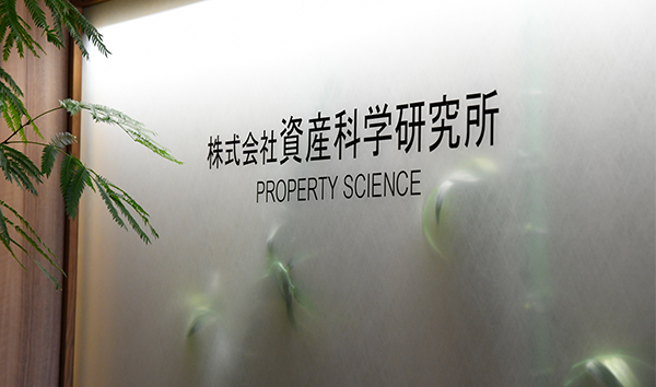 Frosted glass wall with Japanese text and "PROPERTY SCIENCE" written in English, alongside green plant leaves.