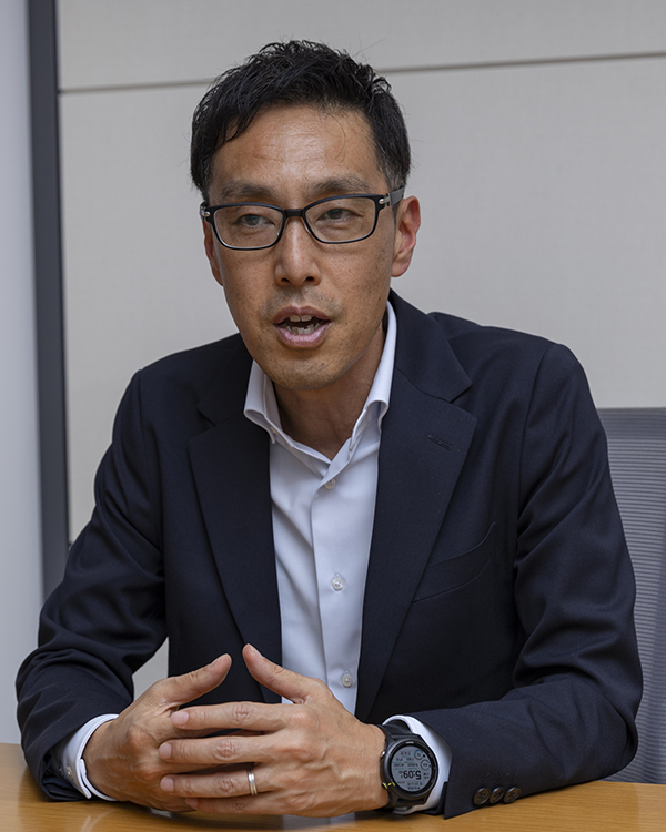 Business professional in glasses and dark suit speaking at a table during an interview for the Saison Technology case study.