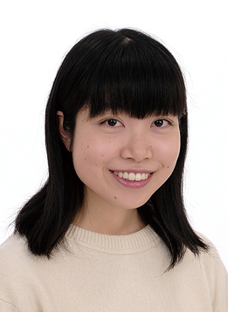Portrait of a smiling woman with black hair in a cream sweater, facing forward against a plain white background.
