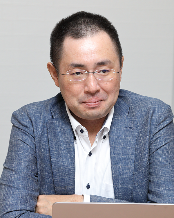 A business portrait of a person in a blue suit jacket and white shirt, seated at a desk, with a neutral background. Suitable for use in solution case studies or business-related content.