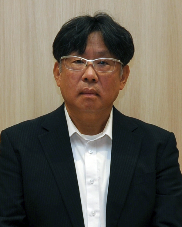 Portrait photo of an individual in a dark suit and white shirt, wearing glasses, featured for the Toppan Shimoda Yasuyuki Shimoda case study.