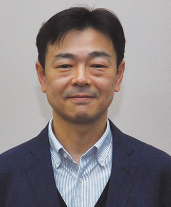 Portrait of Enomoto Kei, a speaker from Fujifilm, wearing a business suit and striped shirt, against a neutral background.
