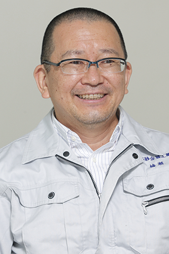 A portrait photo of a smiling individual in glasses and a light gray work uniform, used for the Takasago case study.
