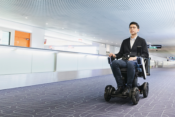 A person in a motorized wheelchair navigating through a modern, spacious airport corridor.