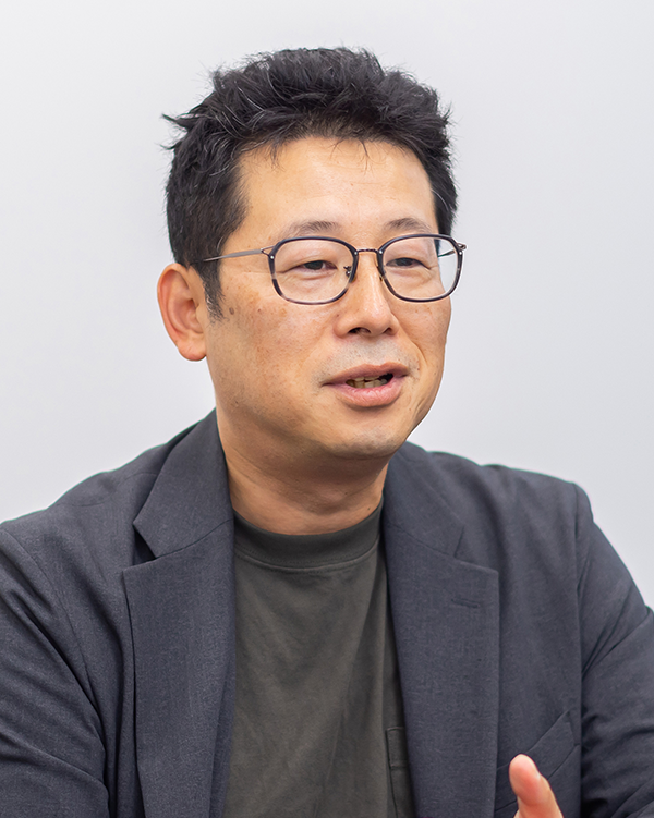 A portrait photograph of a person in a dark jacket and glasses, featured in the EXNOA case study.
