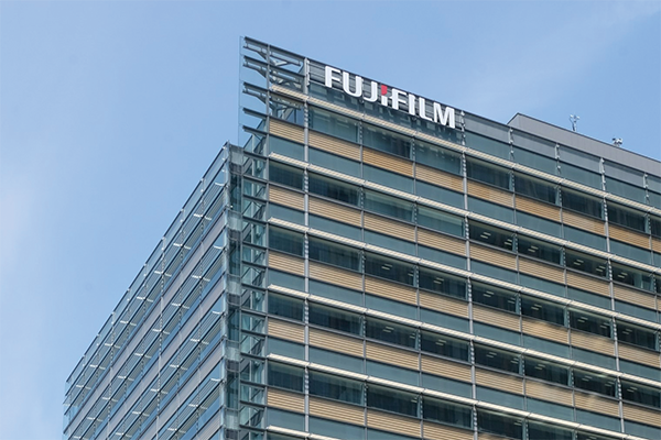 Exterior view of the Fujifilm headquarters building in Tokyo, Japan, featuring modern architectural design with glass and metal elements.