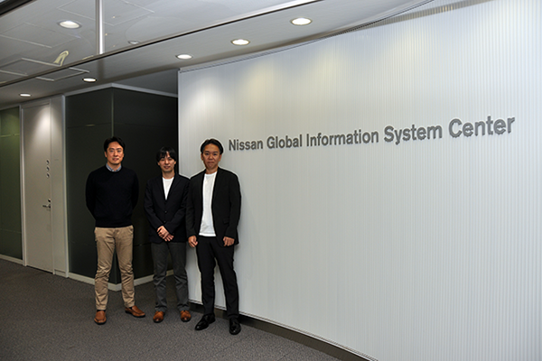 "Nissan Global Information System Center sign on a white wall in a modern office setting."