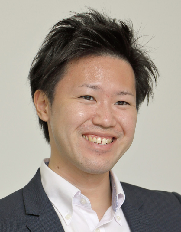 A professional headshot photo of a smiling man wearing business attire, including a suit jacket and white shirt, against a plain background.