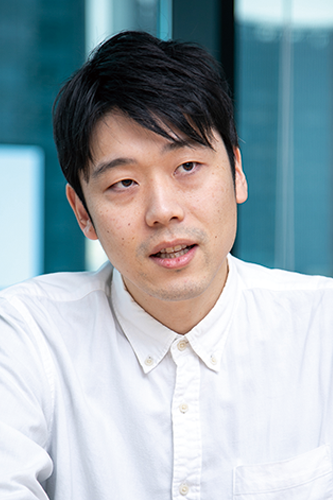 A portrait of a person wearing a white shirt, seated in an office environment. This image represents a member from Softbrain as part of a solution case study.