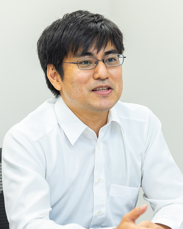 A person wearing a white button-up shirt, seated indoors.