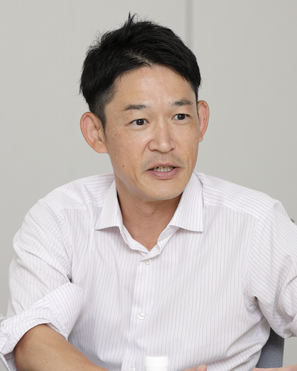 Portrait of a speaker featured in the Furuno case study, wearing a light-colored, collared shirt, photographed indoors against a neutral background.