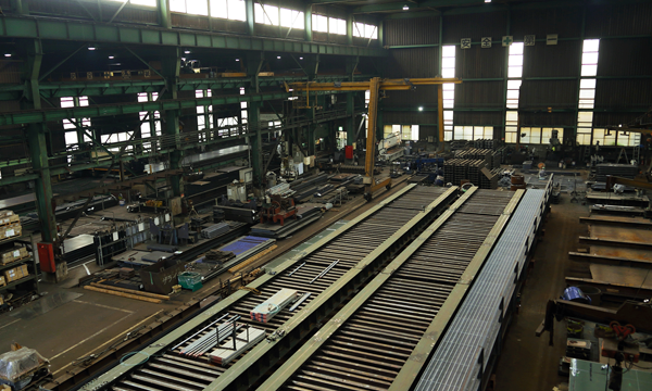 Interior view of the Takasago Metal Industry factory, showing manufacturing equipment and industrial machinery in a spacious facility.