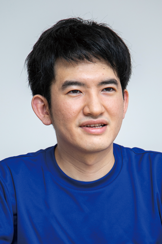 A person wearing a blue shirt against a plain background.