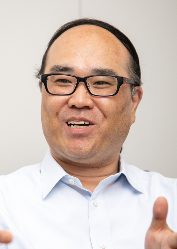 A person wearing a light blue collared shirt, gesturing with their hands.