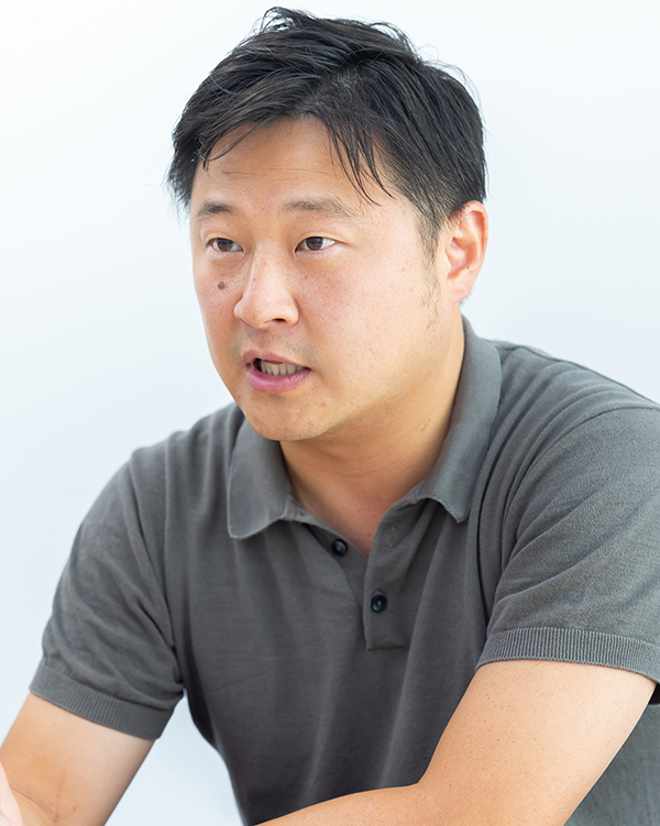 A portrait of a speaker featured in the SSMarket case study, wearing a short-sleeve polo shirt and speaking with an expressive gesture.