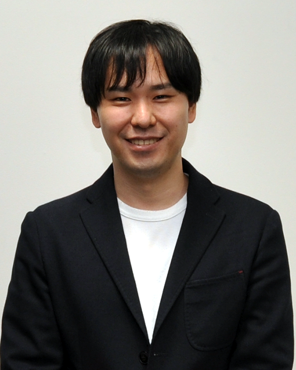 A person smiling and wearing a dark blazer over a white shirt, standing in front of a plain light background. Used for solution case studies.