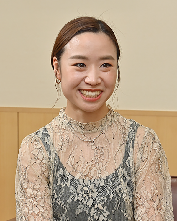 A portrait of a smiling woman in a floral lace top, photographed indoors, used for the Takihyo case study interview.