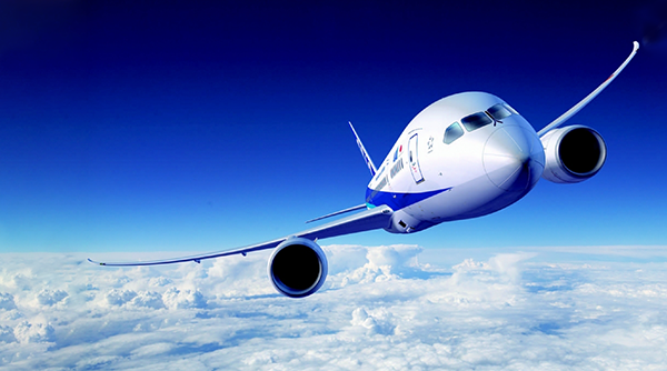 A Boeing 787 aircraft from ANA Airlines is flying above the clouds in a clear blue sky. This image is used for an AWS case study about ANA Airlines.