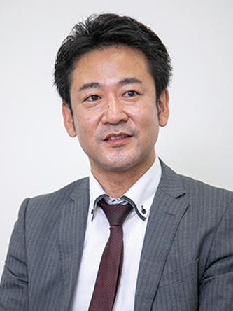 Portrait of a businessman wearing a gray suit and tie against a plain background.