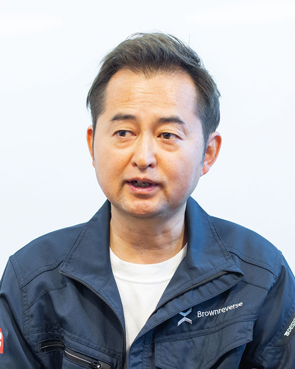 Portrait of a Japanese male speaker wearing a dark blue Brownreverse jacket, photographed against a light background.