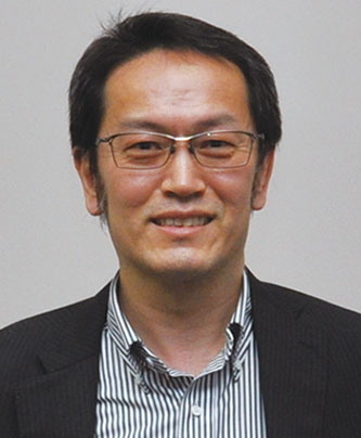 Portrait of a speaker for the FUJIFILM case study, featuring a man wearing glasses, a striped shirt, and a dark blazer, smiling at the camera.