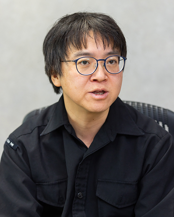 Portrait photograph of a person in glasses and a black shirt, featured in the Asahi Shimbun case study.